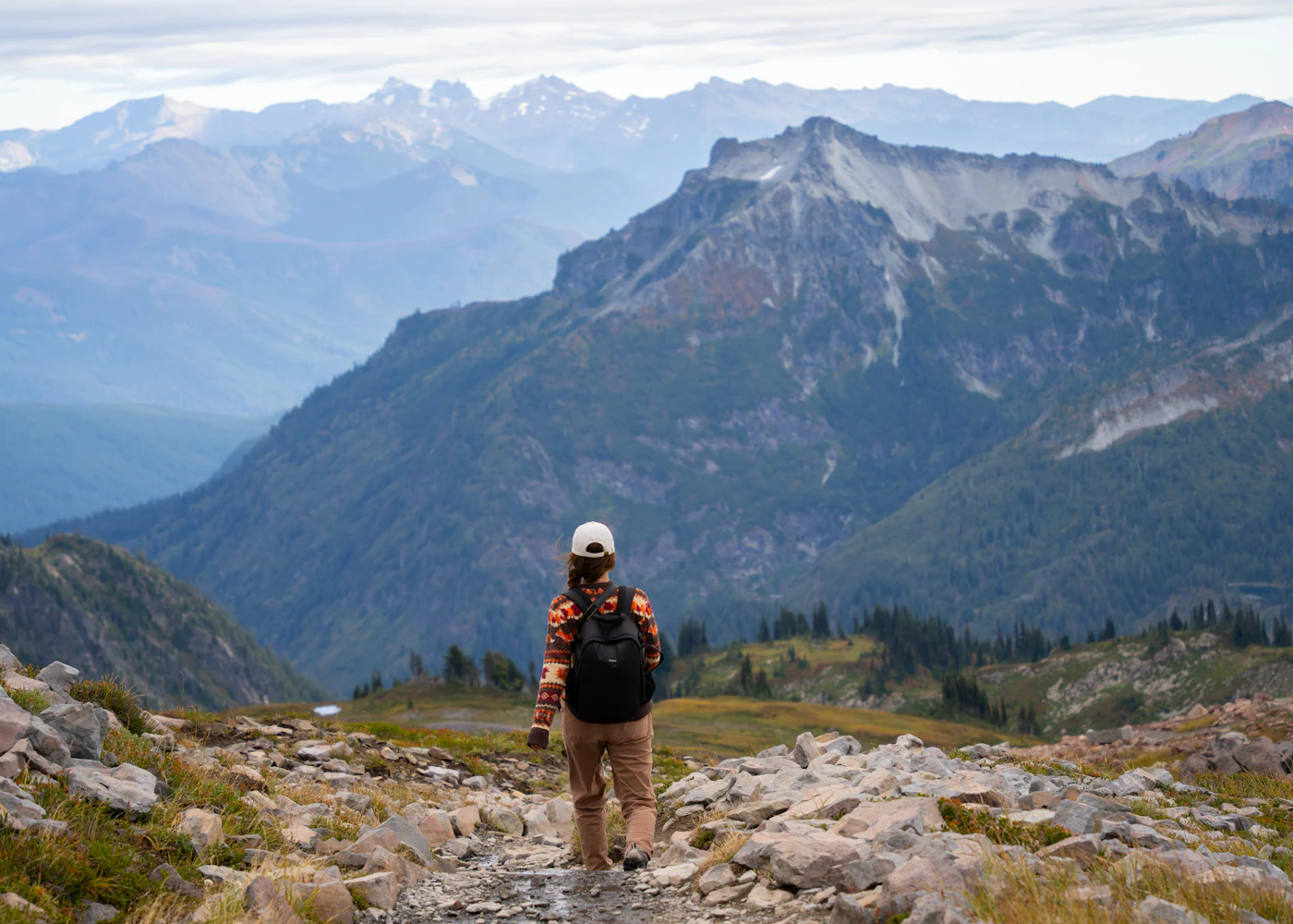 A backpacker seen from behind on a mountain trail in Mount Rainier National Park